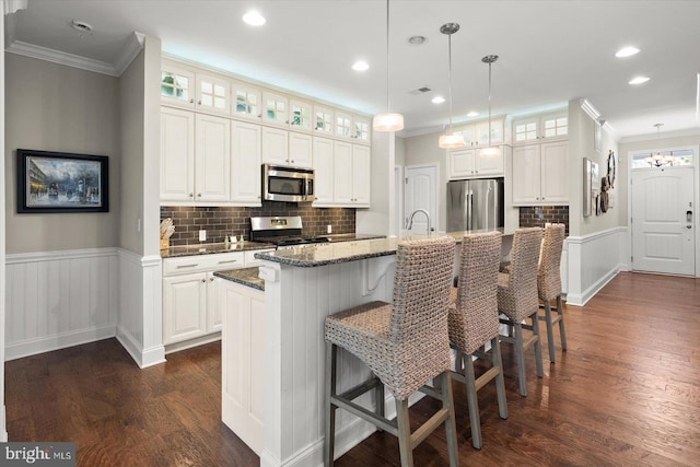 kitchen with dark wood-style floors, appliances with stainless steel finishes, and wainscoting