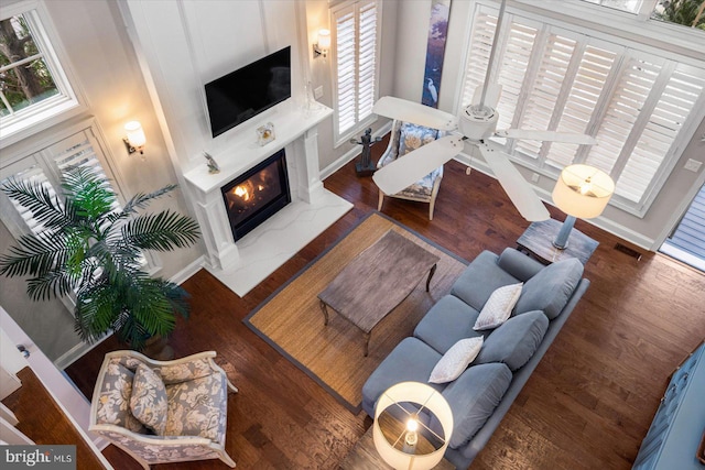 living area with visible vents, a fireplace, baseboards, and wood finished floors