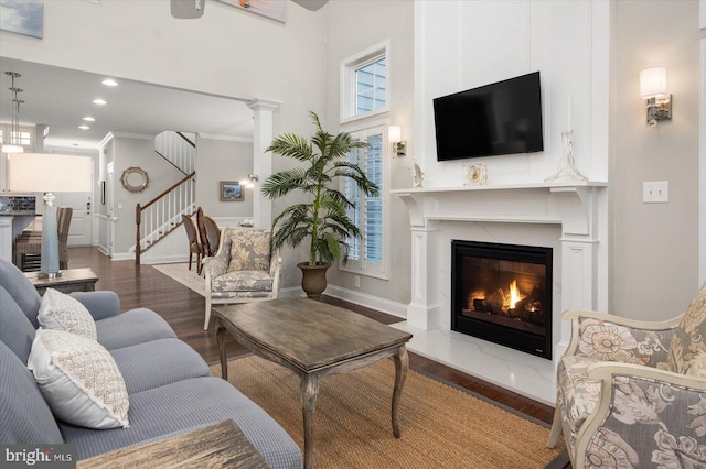 living room with stairway, wood finished floors, baseboards, and a glass covered fireplace