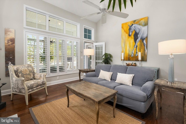 living area with baseboards, a high ceiling, ceiling fan, and wood finished floors