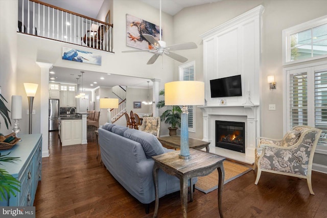 living room with stairway, dark wood-style floors, a large fireplace, and ceiling fan