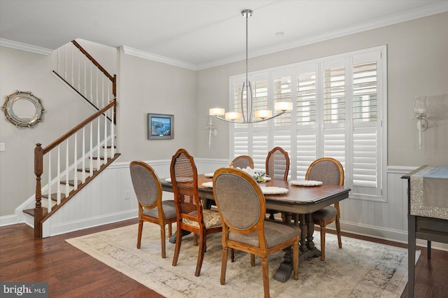 dining space with wood finished floors, ornamental molding, stairs, wainscoting, and a notable chandelier