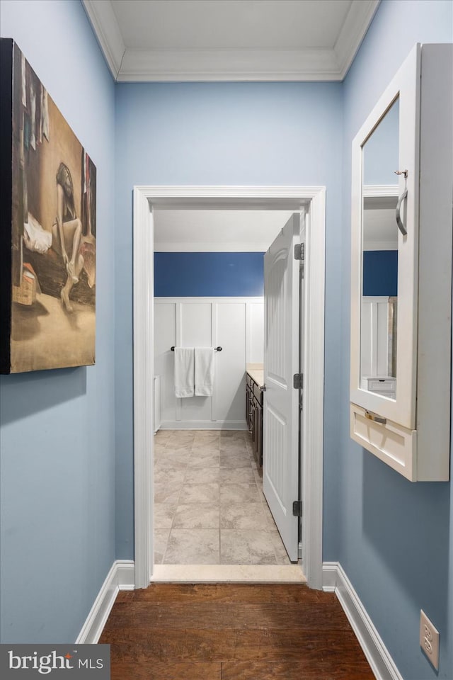 corridor featuring wood finished floors, baseboards, and ornamental molding