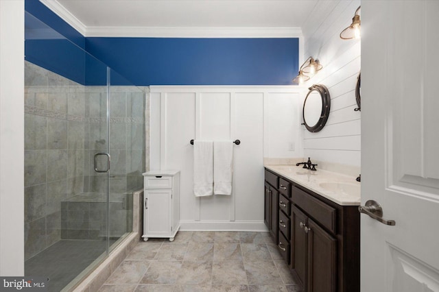 full bathroom with a sink, double vanity, a stall shower, and crown molding