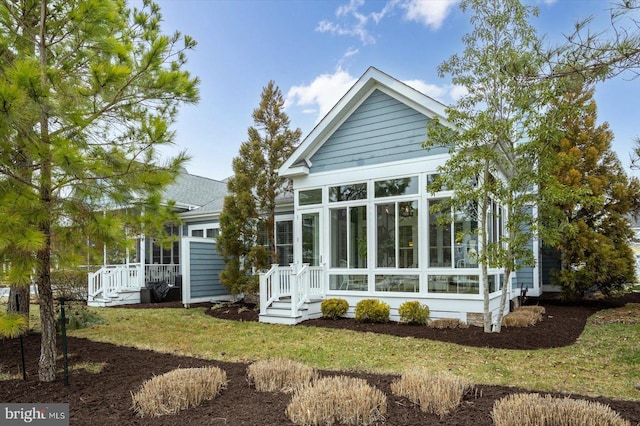 rear view of property featuring a lawn and a sunroom