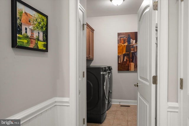 laundry room with light tile patterned floors, a wainscoted wall, visible vents, cabinet space, and separate washer and dryer