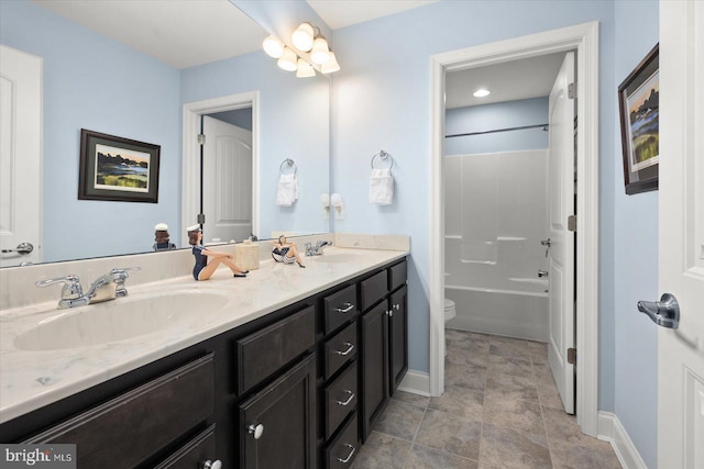 bathroom with double vanity, toilet, baseboards, and a sink