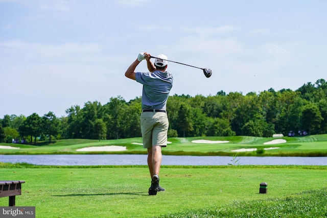 view of home's community with golf course view, a water view, and a yard