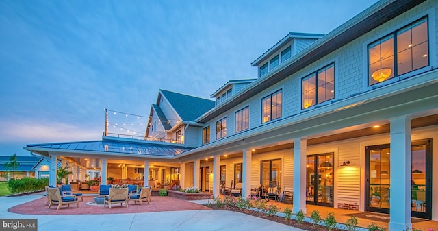 back of property at dusk with an outdoor living space, metal roof, a patio, and a standing seam roof