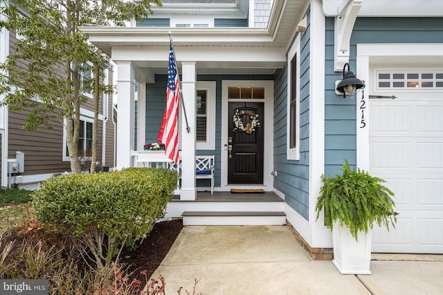 view of exterior entry featuring covered porch and a garage