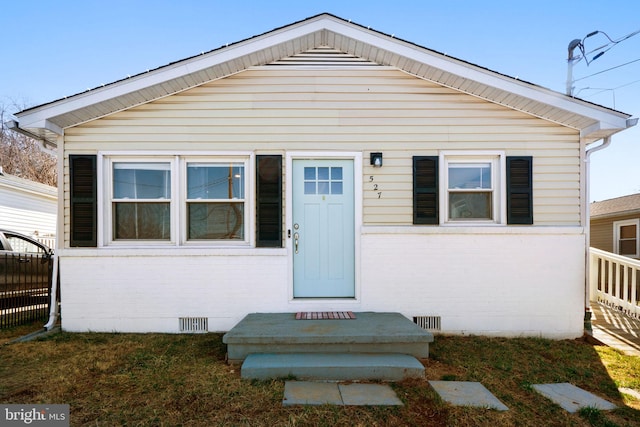 bungalow-style house featuring fence, brick siding, and crawl space