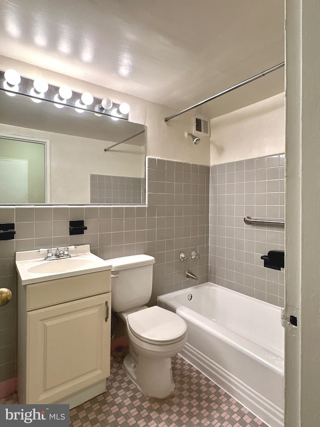full bathroom with tile walls, washtub / shower combination, toilet, and vanity