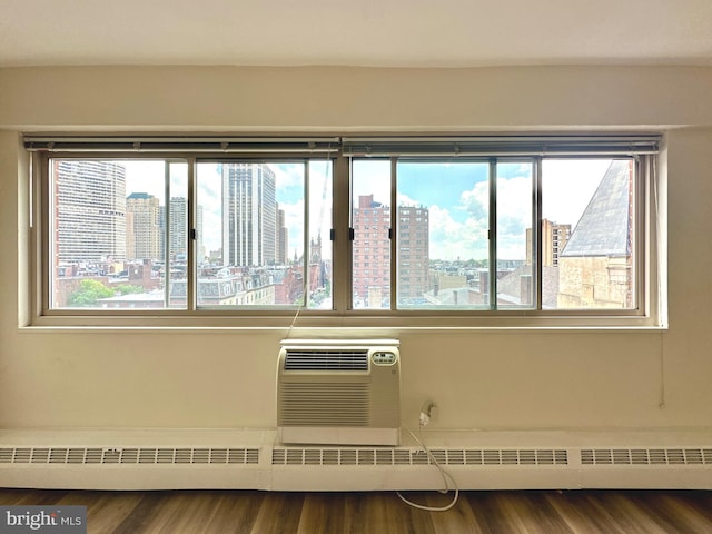 empty room with healthy amount of natural light, wood finished floors, a view of city, and a wall unit AC