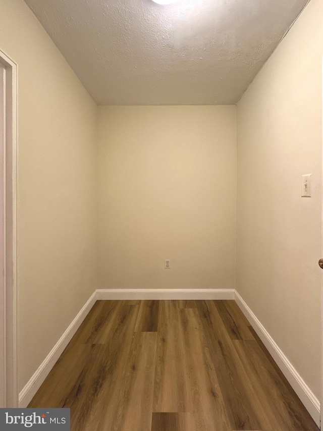 empty room with wood finished floors, baseboards, and a textured ceiling