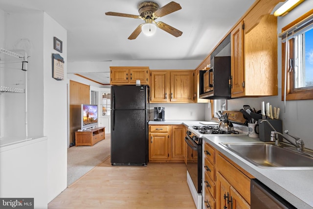 kitchen with range with gas cooktop, light countertops, stainless steel dishwasher, freestanding refrigerator, and a sink