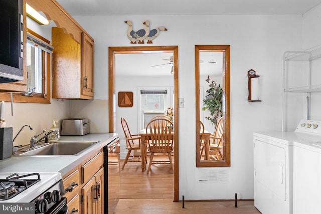 kitchen with dishwasher, stainless steel microwave, washing machine and clothes dryer, light wood-type flooring, and a sink