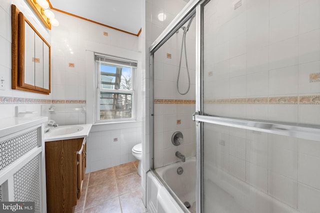 full bathroom with shower / bath combination with glass door, tile walls, toilet, vanity, and tile patterned floors