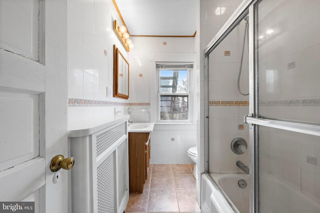 full bath with shower / bath combination with glass door, tile walls, toilet, vanity, and tile patterned flooring