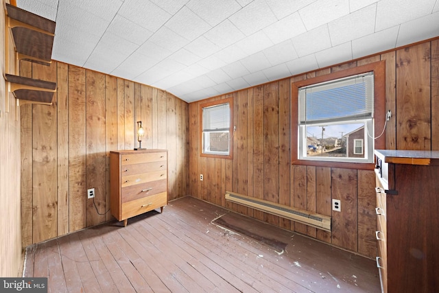 interior space with wooden walls, baseboard heating, and hardwood / wood-style floors