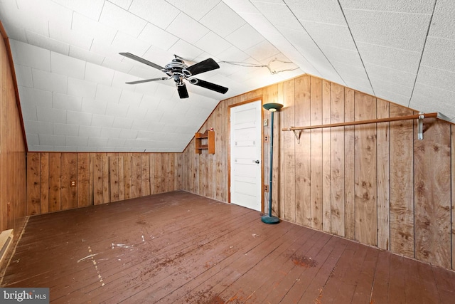 additional living space featuring a ceiling fan, lofted ceiling, wooden walls, and hardwood / wood-style floors