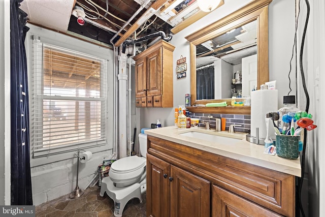 bathroom featuring stone finish floor, vanity, and toilet