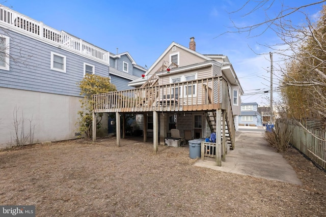 rear view of house featuring a deck, a chimney, fence, and stairway