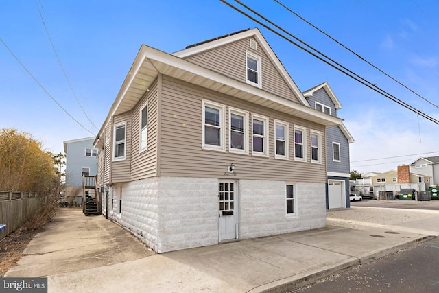 view of home's exterior featuring a garage, concrete driveway, and fence