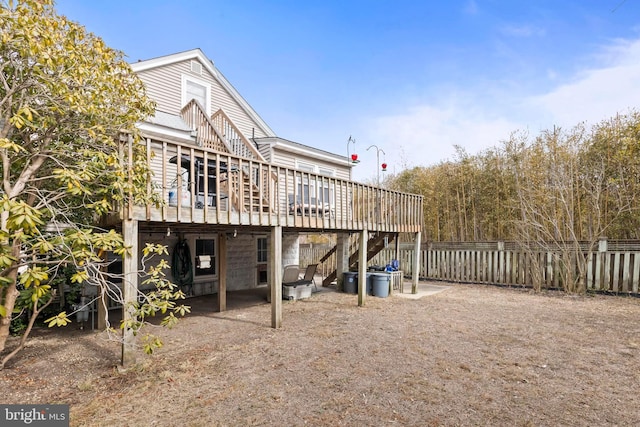 back of property featuring stairs, a wooden deck, and fence