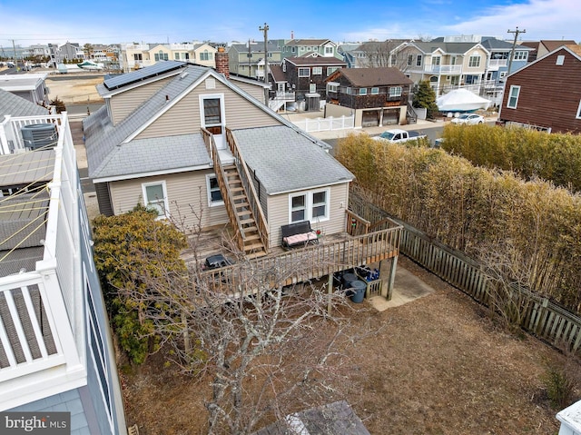 back of property featuring fence private yard, stairs, a residential view, and solar panels