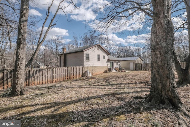 view of side of home with fence and a chimney