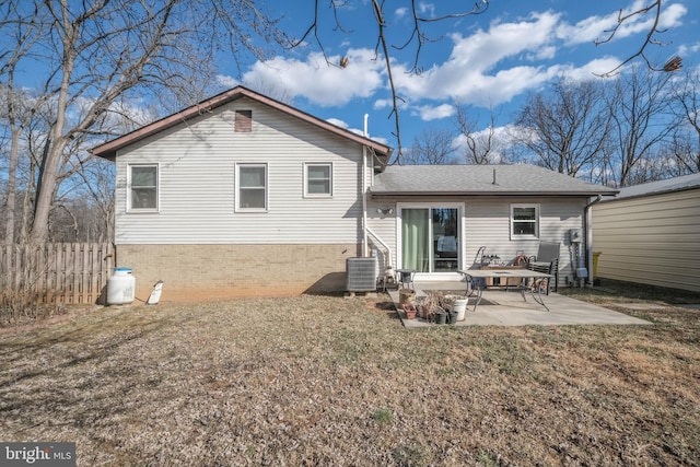 back of property with brick siding, roof with shingles, a patio area, fence, and central AC