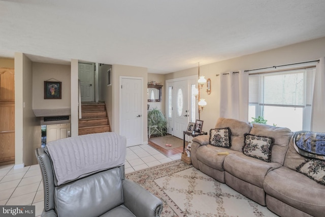 living room featuring visible vents, light tile patterned flooring, and stairway