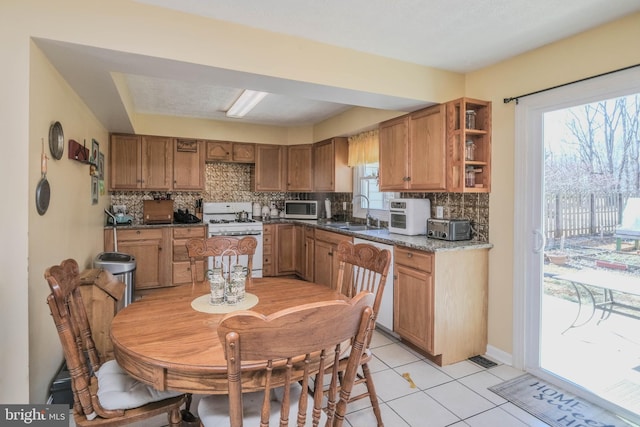 kitchen with white appliances, brown cabinetry, a sink, and decorative backsplash