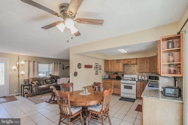 dining space featuring light tile patterned floors, ceiling fan, and a textured ceiling