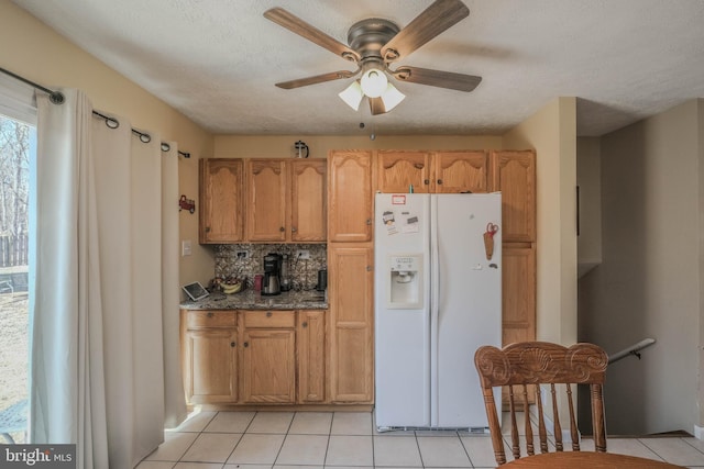 kitchen featuring ceiling fan, a textured ceiling, light tile patterned flooring, white refrigerator with ice dispenser, and decorative backsplash