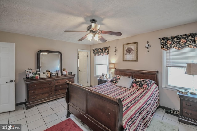 bedroom featuring multiple windows, ceiling fan, a textured ceiling, and light tile patterned floors