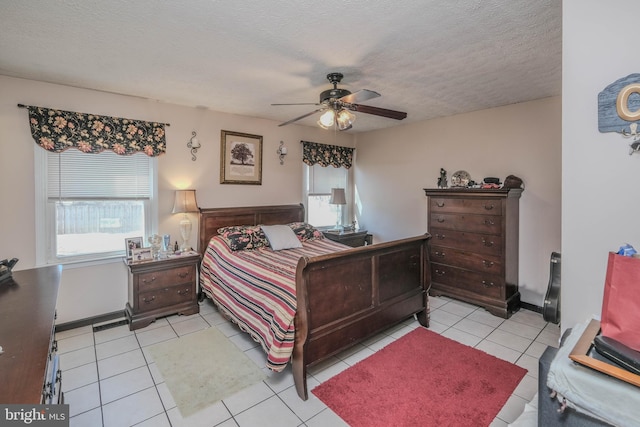 bedroom with light tile patterned floors, multiple windows, a ceiling fan, and a textured ceiling