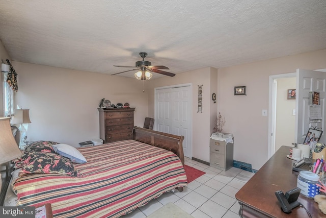 bedroom featuring a closet, light tile patterned flooring, ceiling fan, and a textured ceiling