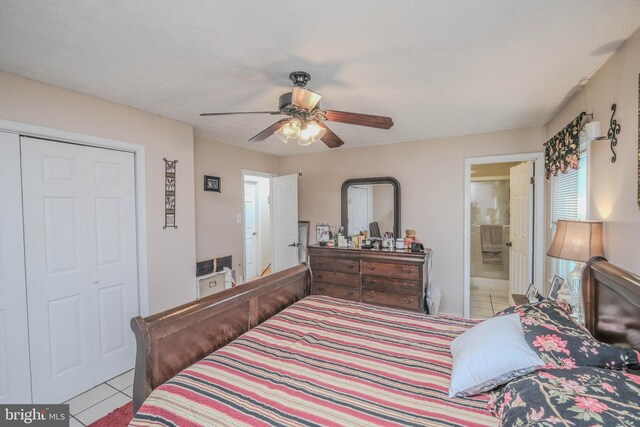 bedroom with light tile patterned floors, a closet, connected bathroom, and a ceiling fan