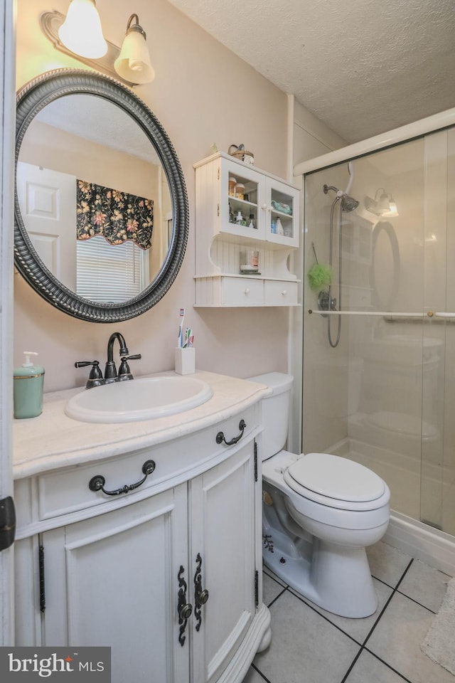 full bathroom with toilet, vanity, a shower stall, a textured ceiling, and tile patterned floors