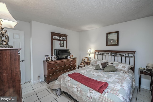 bedroom with a textured ceiling, baseboards, and light tile patterned floors