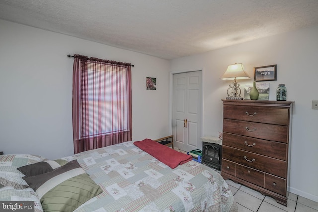 bedroom featuring baseboards, a textured ceiling, and light tile patterned flooring