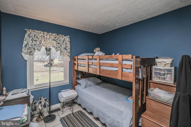 bedroom featuring a textured ceiling, baseboards, and tile patterned floors