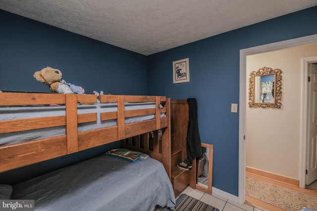 bedroom with baseboards, a textured ceiling, and light tile patterned flooring