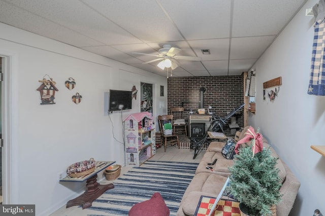 interior space featuring a ceiling fan, a wood stove, and a drop ceiling