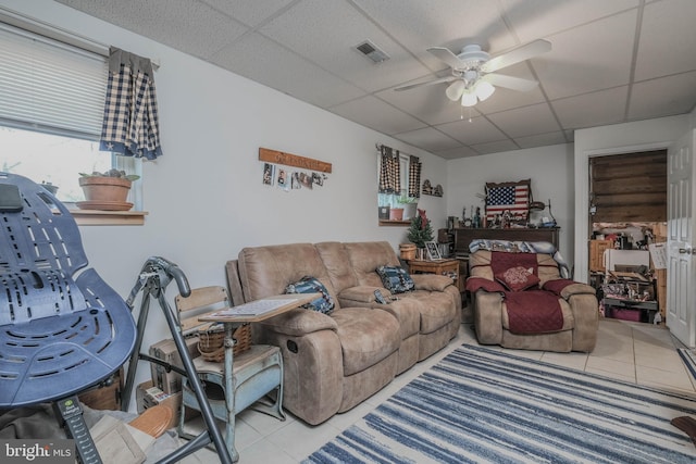 living room with visible vents, ceiling fan, a drop ceiling, and light tile patterned floors