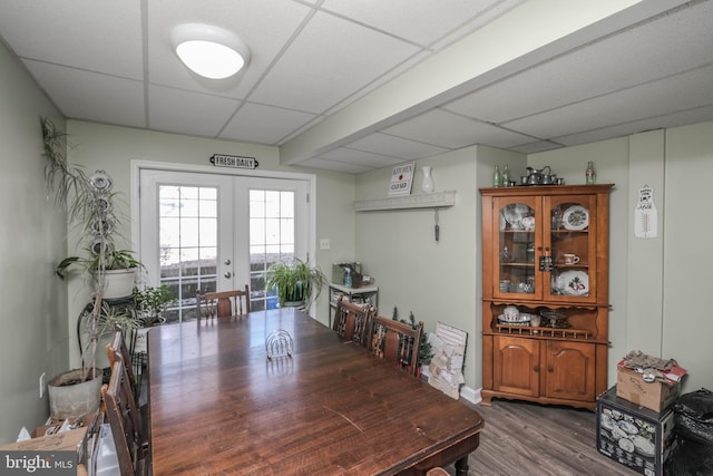 dining space with french doors, a drop ceiling, and wood finished floors