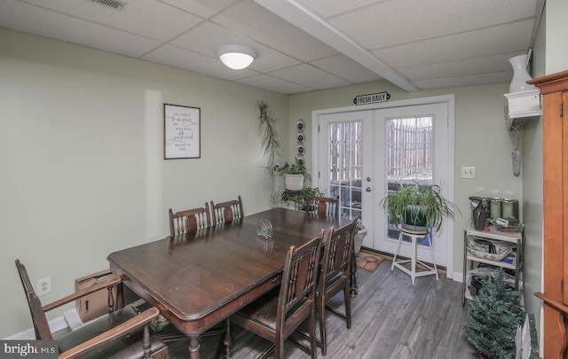 dining space with french doors, dark wood-type flooring, a drop ceiling, and baseboards