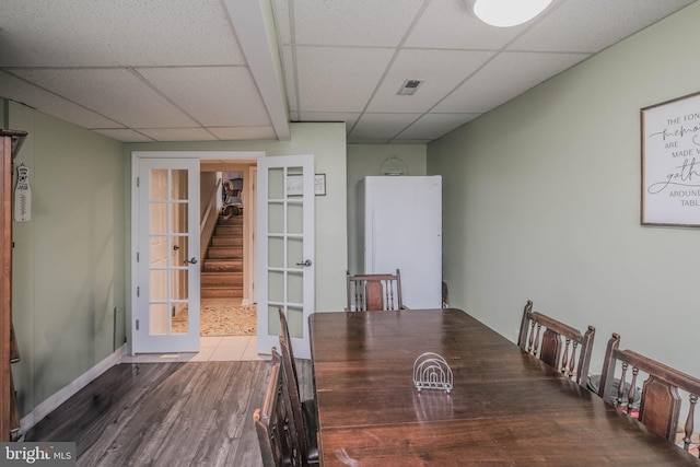 unfurnished dining area featuring visible vents, stairway, wood finished floors, a drop ceiling, and baseboards