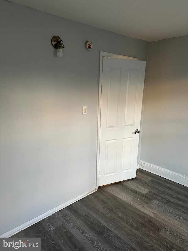 spare room with dark wood-style flooring and baseboards